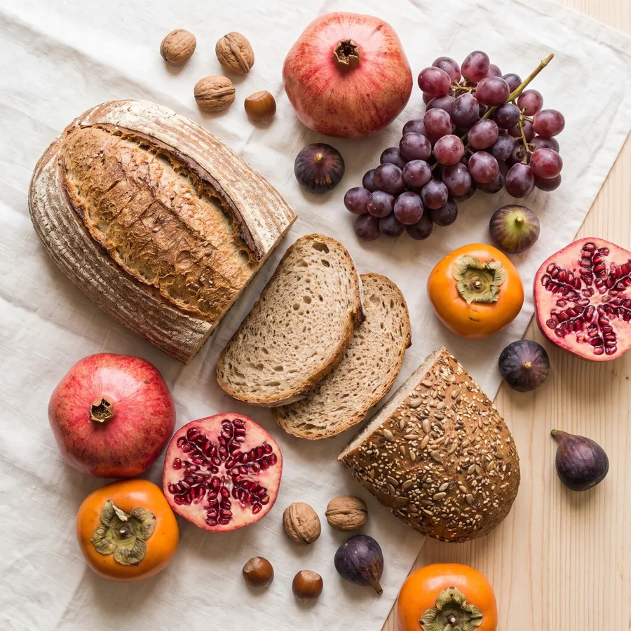 Imagen ilustrativa: pan artesano, fruta y frutos secos de la Vega, bodegón cenital