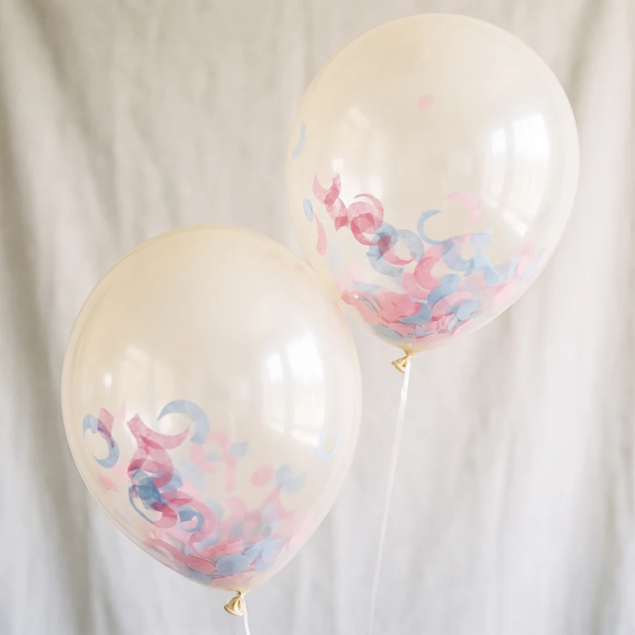 Imagen ilustrativa: dos globos crema con confeti rosa y azul dentro