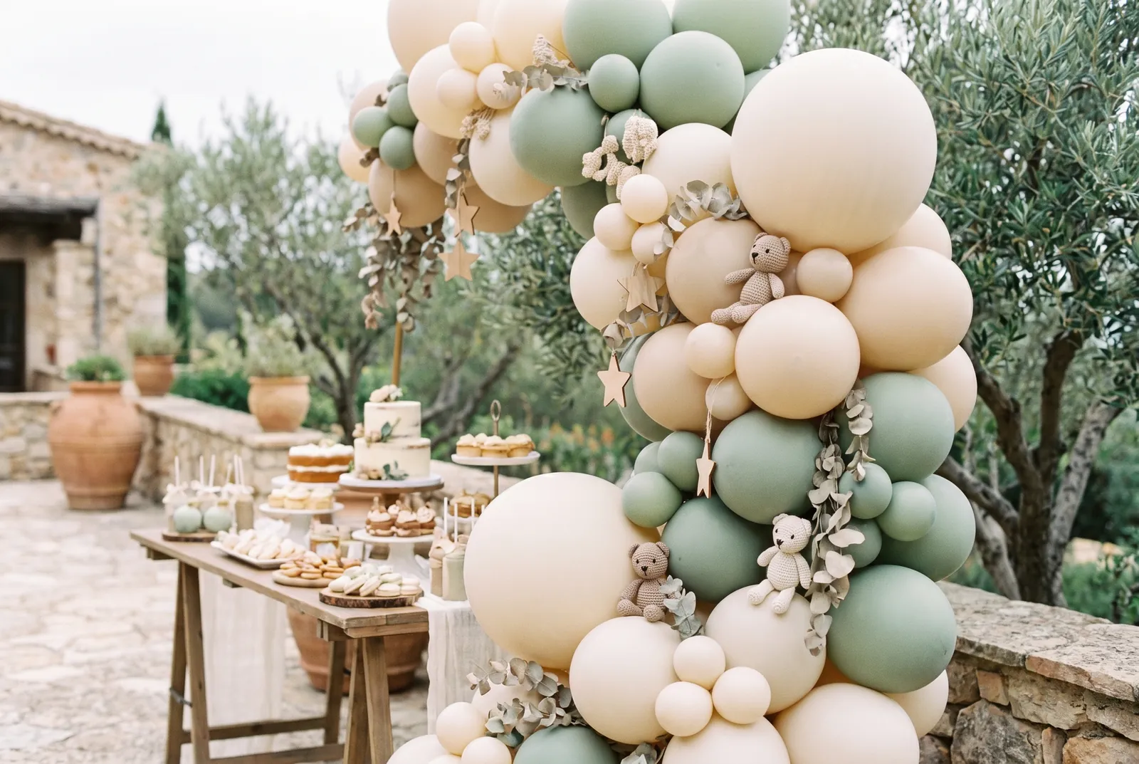 Imagen ilustrativa: arco de globos crema y beige con detalles neutros de bebé y mesa dulce al fondo